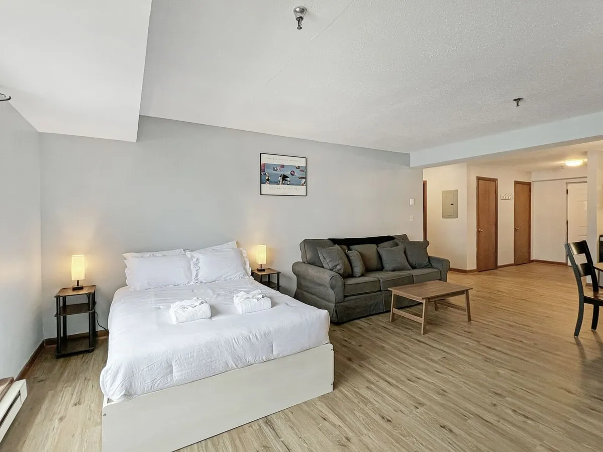 A comfortable interior scene with both the bed and sofa visible, accented by tasteful artwork. The layout invites both relaxation and restful sleep, embodying a mountain retreat vibe.