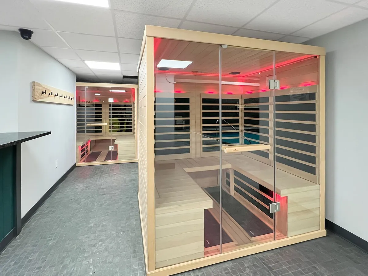 A tranquil wellness area with multiple sauna units, soft lighting fixtures, and sleek glass walls. The atmosphere is serene and calming, perfect for post-exercise relaxation or unwinding after a day on the slopes.