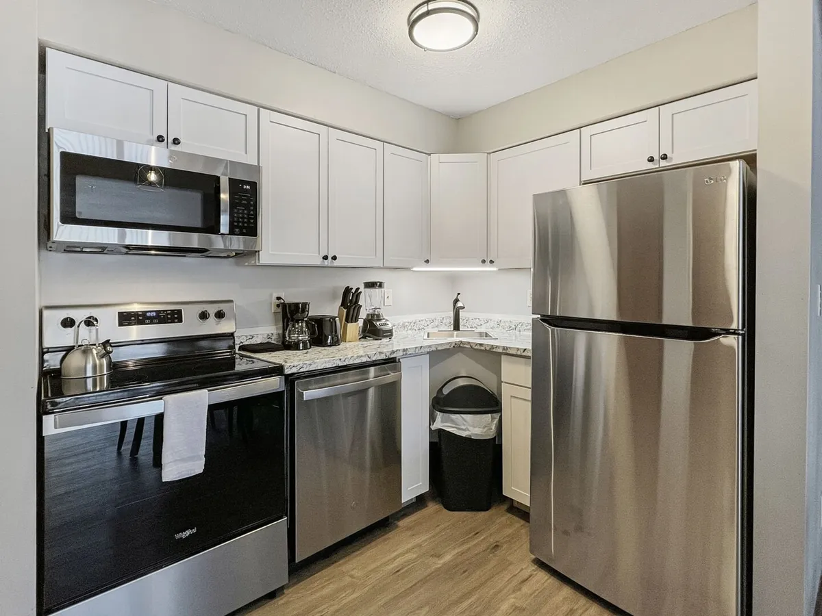 A sleek kitchen with stainless steel appliances, granite countertops, and crisp white cabinetry. The scene emphasizes functionality, ample preparation space, and a clean, inviting atmosphere for both casual cooking and more ambitious culinary projects.