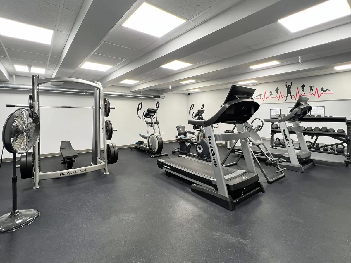 A vibrant, modern fitness center equipped with treadmills, elliptical machines, weights, and other gym equipment. The setting is well-lit and spacious, creating a sense of energy and motivation for post-adventure workouts.