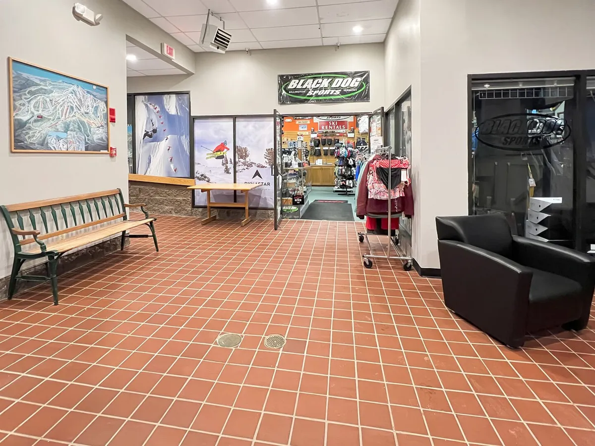The entrance to Black Dog Sports, featuring a well-organized display of sports clothing and gear, benches for seating, and colorful artwork. The setting is bustling yet welcoming, inviting guests to discover local shops and gear up for their Killington adventures.