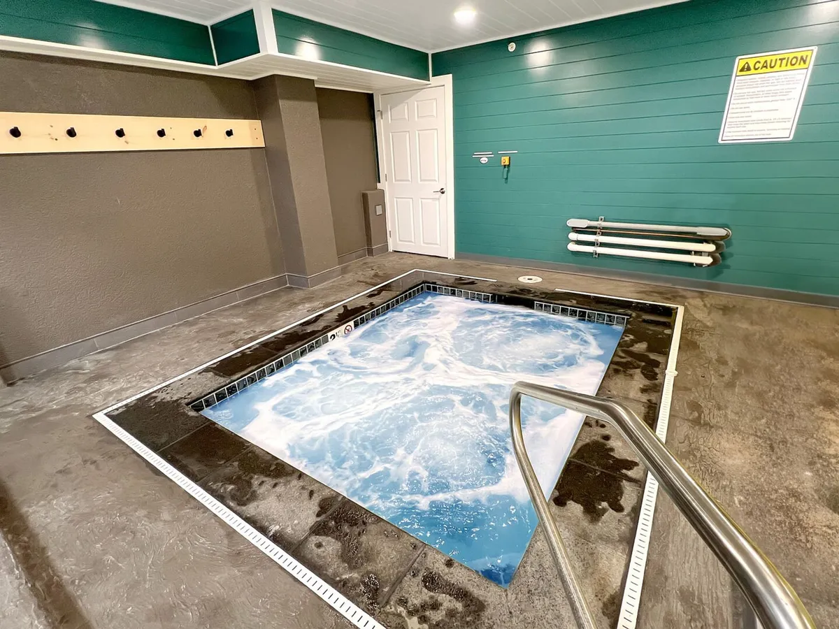A tranquil indoor hot tub area with a soothing color palette, handrail, and inviting warm water. The setting evokes relaxation and rejuvenation after a day of winter adventure.